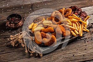 Take away fast food products fried chicken with french fries and nuggets meal, junk food and unhealthy food on a wooden board.