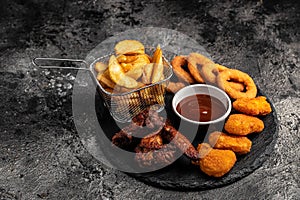 Take away fast food products fried chicken with french fries and nuggets meal, junk food and unhealthy food on a wooden board.