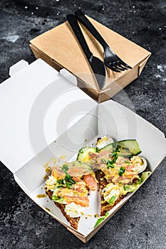 Take away food paper box with sandwich. Black background. Top view