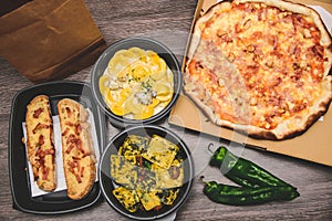 Take away italian pasta food. Pizza with box green peppers, garlic bread, fetuccine and ravioli on plastic box