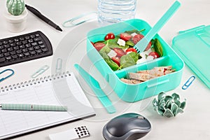Take away lunch box with fresh salad and tuna fish over the offi