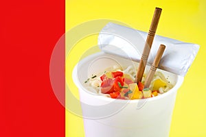 Take away noodles with vegetables on red and yellow background