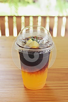 Take away plastic cup of iced black coffee Americano  on wooden table