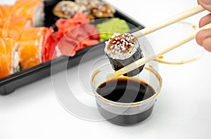 Take away sushi in plastic containers, philadelphia rolls and unagi maki, soy sauce, pink ginger, wasabi, sushi delivery concept