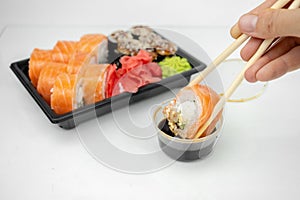 Take away sushi in plastic containers, philadelphia rolls and unagi maki, soy sauce, pink ginger, wasabi, sushi delivery concept