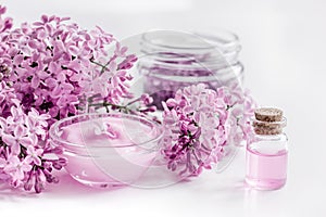 Take bath with lilac cosmetic set and blossom on white table background