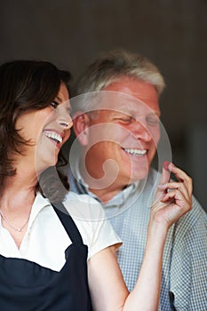 Take a bite, honey. a senior woman feeding her husband a raspberry in the kitchen.