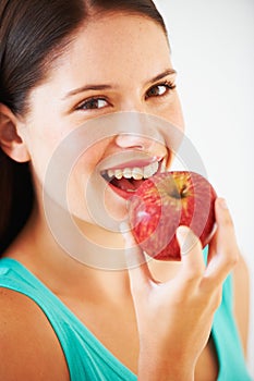 Take a bite from a red apple. Portrait of a beautiful young woman enjoying an apple.