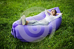 Take a break. Pretty young woman lying on inflatable sofa lamzac while resting on grass in park on the sun