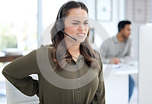 Take a break, your back deserves it. a young businesswoman experiencing back pain while using a headset and computer at