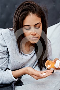 Take care, flu season is here. a young woman taking medication while recovering from an illness in bed at home.