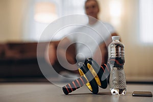 Take care of your body Close up sports equipment. Exercise Wheel. Plastic water bottle. Blurred man in easy seat pose