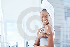 Take care of your body. a young woman applying moisturizer to her body.