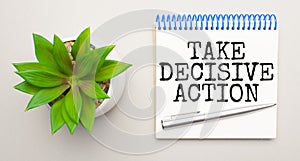 TAKE DECISIVE ACTION is written in a white notepad near a clipboard, calculator, green plant, glasses and a pen on a yellow and