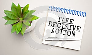 TAKE DECISIVE ACTION is written in a white notepad near a clipboard, calculator, green plant, glasses and a pen on a yellow and