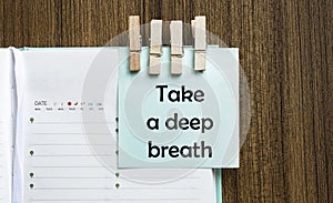 Take a deep breath notes paper and a clothes pegs on wooden background