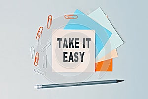 Take it easy - text on sticky note paper on gray background. Closeup of a personal agenda. Top view