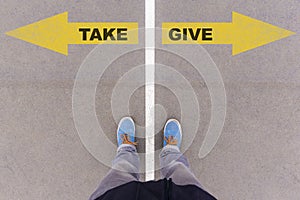 Take or give text arrows on asphalt ground, feet and shoes on fl