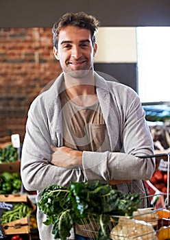 He always take the healthy choice. Portrait of a young man in a grocery store holding a basket full of fresh produce.