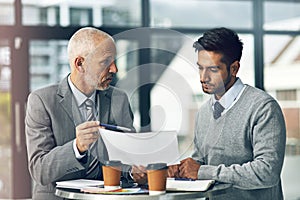 Take a look at this contract. two businessmen looking over some paperwork in the office.