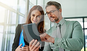 Take a look at this. two businesspeople looking at a tablet in the office.