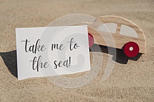 TAKE ME TO THE SEA text on paper greeting card and car summer vacation decor. Sandy beach sun coast. Holiday concept