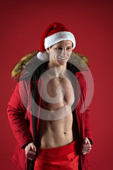 Take off winter jacket. Healthy body. Santa claus diet. Athlete man wear santa hat. Sexy athletic macho in santa claus