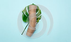 Take-out coffee paper cups on green leaf of monstera. Top view on blue background
