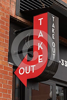 Take out red sign with arrow on a building near fast food restaurant or cafe.