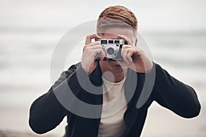 Take a picture, itll last longer. a man taking pictures with his camera on the beach.