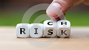 Take a risk and getting rich concept. Hand turns dice and changes the word `risk` to `rich`.