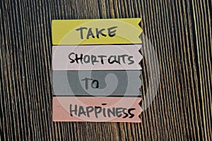 Take Shortcuts to Happiness write on sticky notes isolated on Wooden Table. Motivation or Insipiration Concept