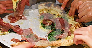 Take simultaneously with your hands hot slices of pizza with prosciutte spinach and parmesan close-up, pizza margarita