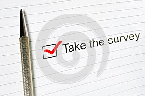 Take survey check box with a pen on lined paper background