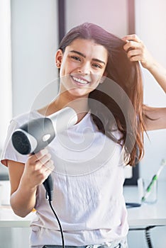 Take the time to care for your hair. Portrait of a beautiful young woman blowdrying her hair in the bathroom at home.