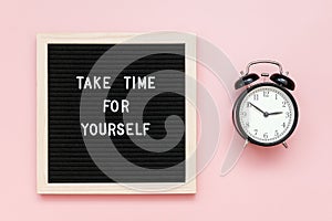 Take time for yourself. Motivational quote on letterboard and black alarm clock on pink background. Top view Flat lay Copy space