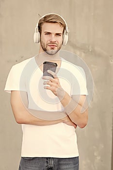 Takeaway beverage on the move. Handsome man listen to music drinking coffee. Young guy hold drinking cup outdoors