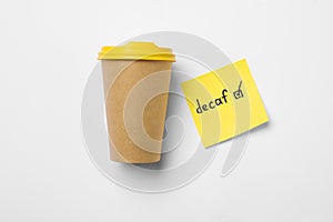 Takeaway coffe cup, note with word Decaf and checkbox on white background, flat lay