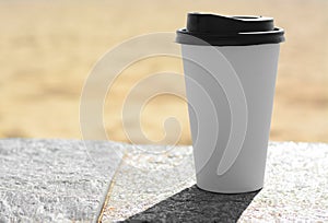 Takeaway coffee cup on stone surface outdoors. Space for text