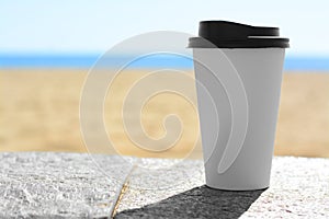 Takeaway coffee cup on stone surface outdoors. Space for text