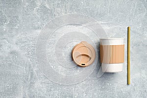 Takeaway coffee mug with bamboo drinking straw on stone background. Zero waste, sustainable lifestyle concept. Flat lay, top view