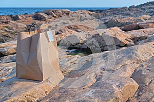 Takeaway food craft bag at the isolated rocky ocean beach