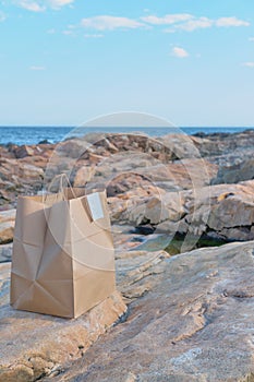 Takeaway food craft bag at the isolated rocky ocean beach