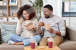 Happy couple with takeaway food and drinks at home