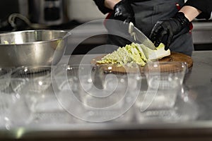 takeaway food in the restaurant. Close-up of a chef& x27;s hands in gloves preparing a cabbage salad. Disposable lunch boxes