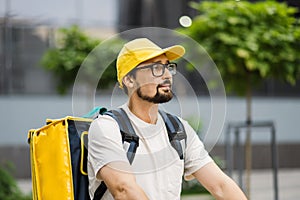 Takeaway, portrait of delivery boy on scooter with yellow isothermal backpack.