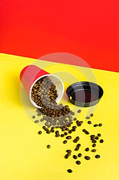 Takeaway red paper coffee cup with black cap on red and yellow background with pouring roasted beans