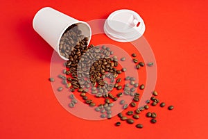 Takeaway white paper coffee cup with cap on red background with pouring roasted beans out of it