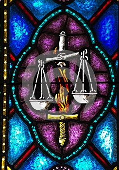 Stained Glass image of the Flaming Sword that guards Paradise and the Scales of Justice