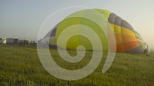 Takeoff air balloon at sunset, air balloons start fly from grass field at summer sunset, air balloons on field with